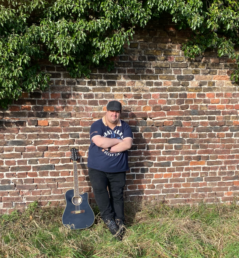 SMW mit Gitarre an einer alten Ziegelsteinmauer